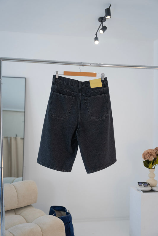 Back view of black Stingem cotton shorts hanging on clothing rack.