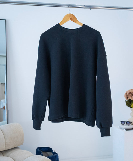 Front view of black Stingem cotton jumper hanging on wooden hanger.