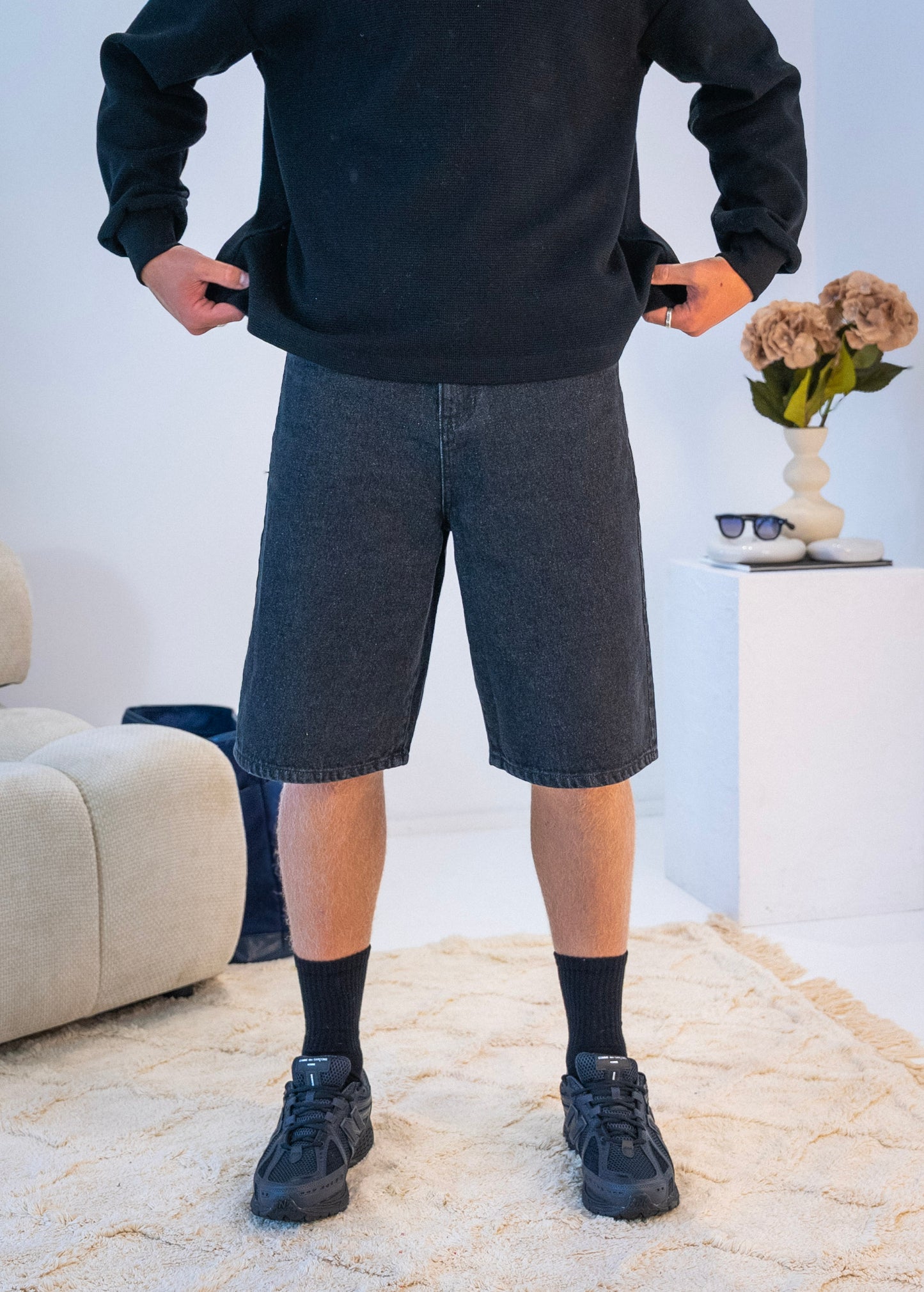 Front view of model wearing black Stingem cotton shorts styled with black jumper.