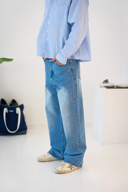Side view of model wearing blue washed Stingem cotton jeans styled with striped shirt.