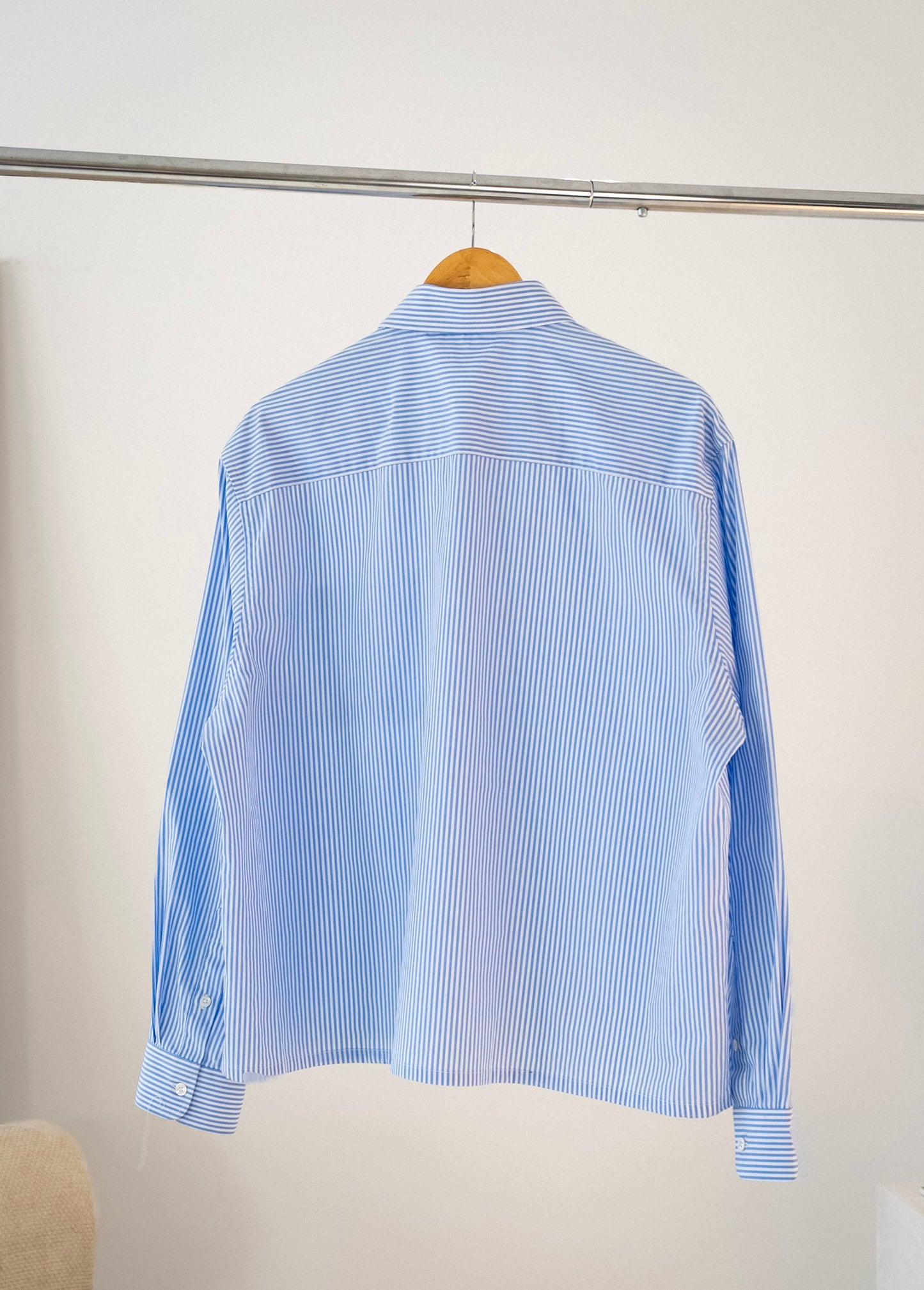 Back view of white and blue striped Stingem cotton shirt hanging on clothing rack.