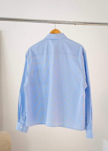 Back view of white and blue striped Stingem cotton shirt hanging on clothing rack.