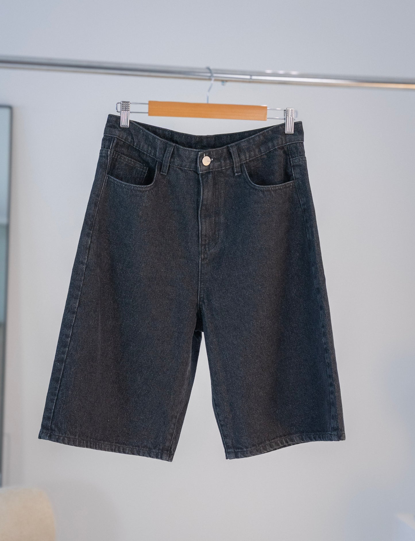 Front view of black Stingem cotton shorts hanging on wooden hanger.
