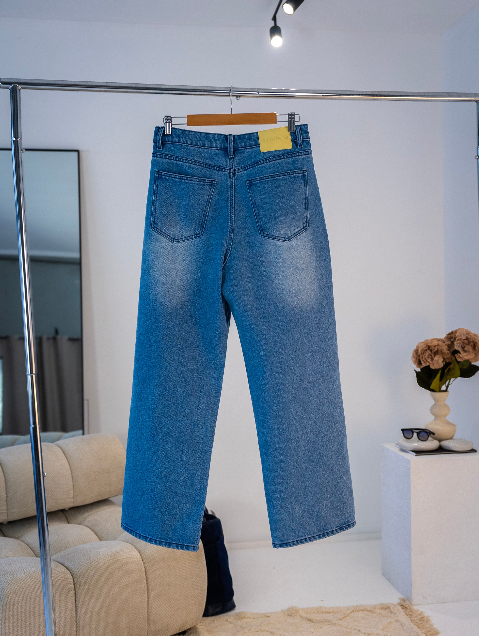 Back view of blue washed Stingem cotton jeans showing rear pockets and logo patch.