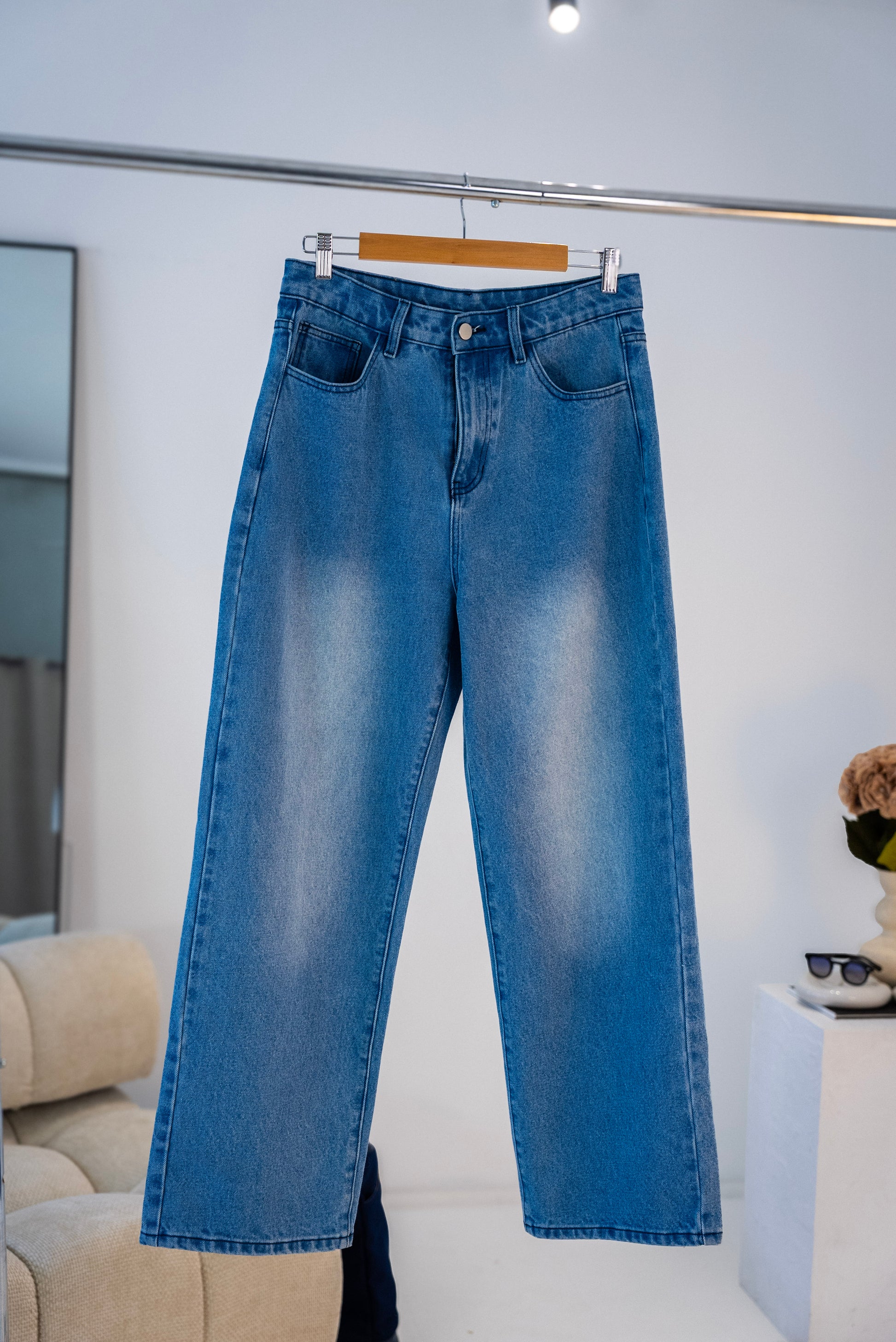 Front view of blue washed Stingem relaxed fit jeans hanging on clothing rack.