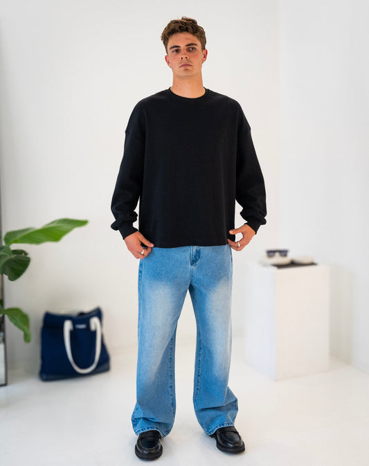 Front view of model wearing black Stingem cotton jumper with relaxed boxy fit.