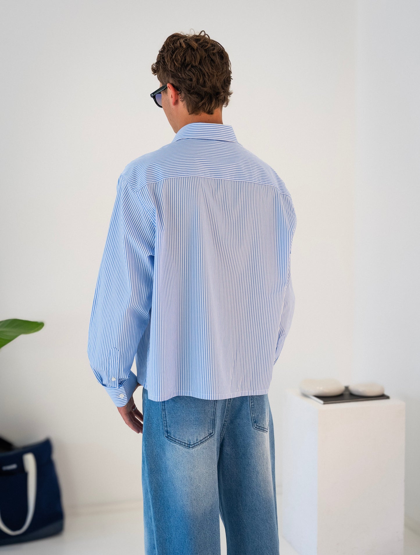 Rear view of model wearing white and blue striped Stingem cotton shirt.