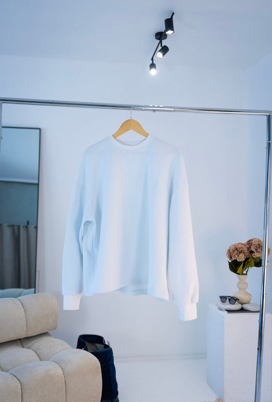 Front view of white Stingem cotton jumper hanging on wooden hanger.